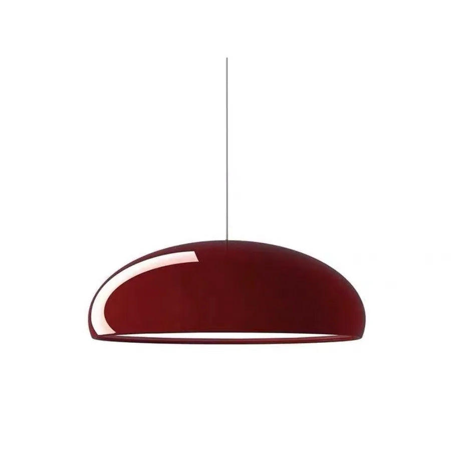 Orange iron Danish-style pendant lamp with adjustable cable above a restaurant table.