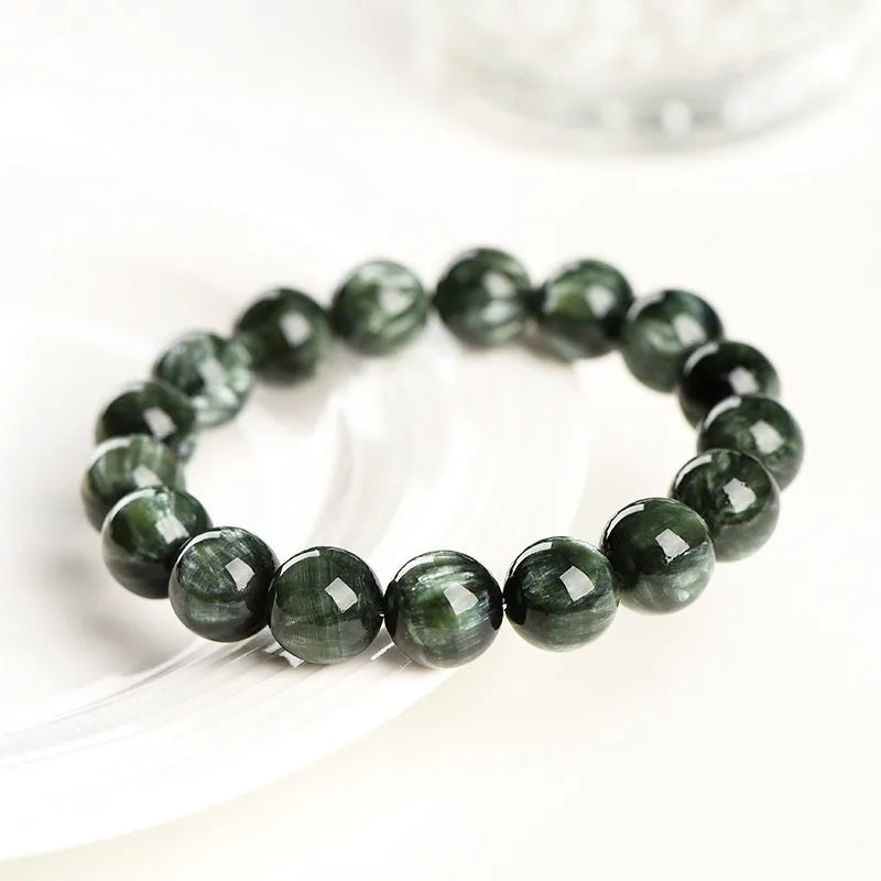 A bracelet made of polished green dragon crystal round beads with a geometric Ruyi design element.