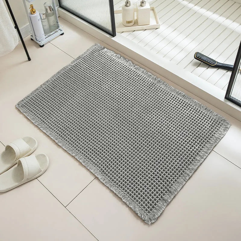A beige checkered non-slip polyester bathroom carpet on a tiled floor.