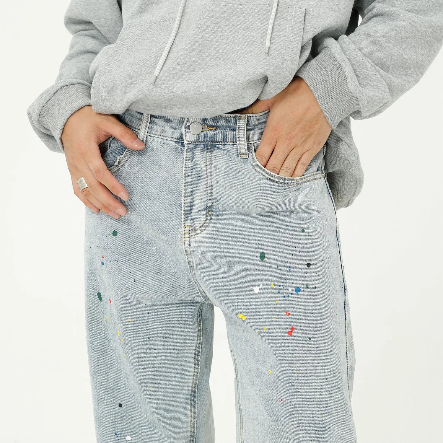 Light blue straight loose jeans with paint splash and washed finish, mid-waist zip fly, laid flat on neutral background