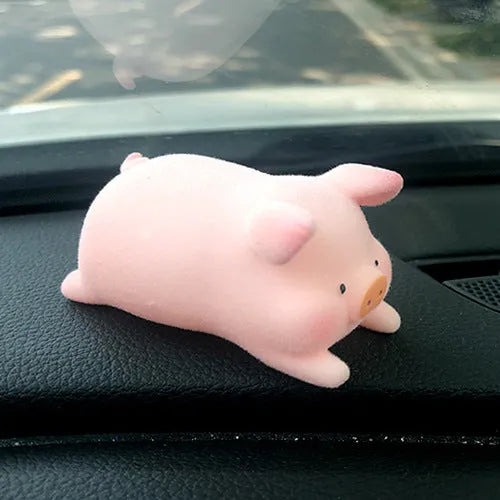 A cute cartoon pig resin figurine car decoration accessory on a dashboard.
