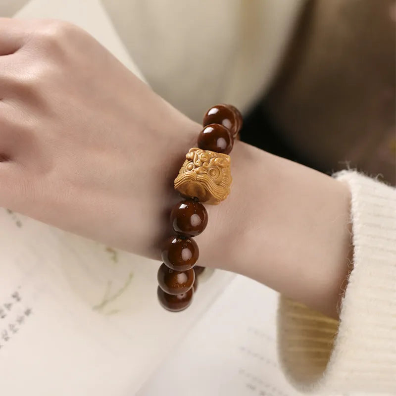 Hand-woven bracelet with 13mm round beads showing lion design in ivory nut, bodhi or sandalwood style