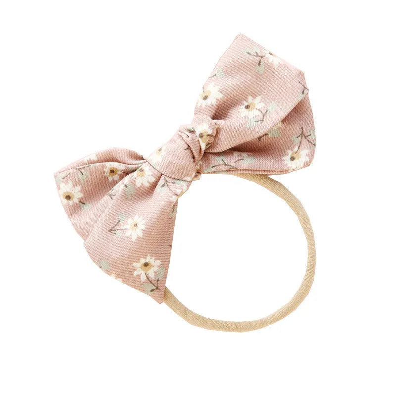 Children's cloth hair band with a white knotted bow, shown against a colour swatch background.