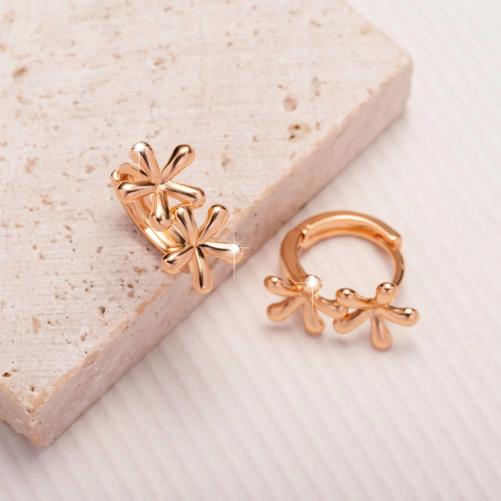 Silver rose gold electroplated circular waterdrop flower earrings with butterfly backs on a grey background.