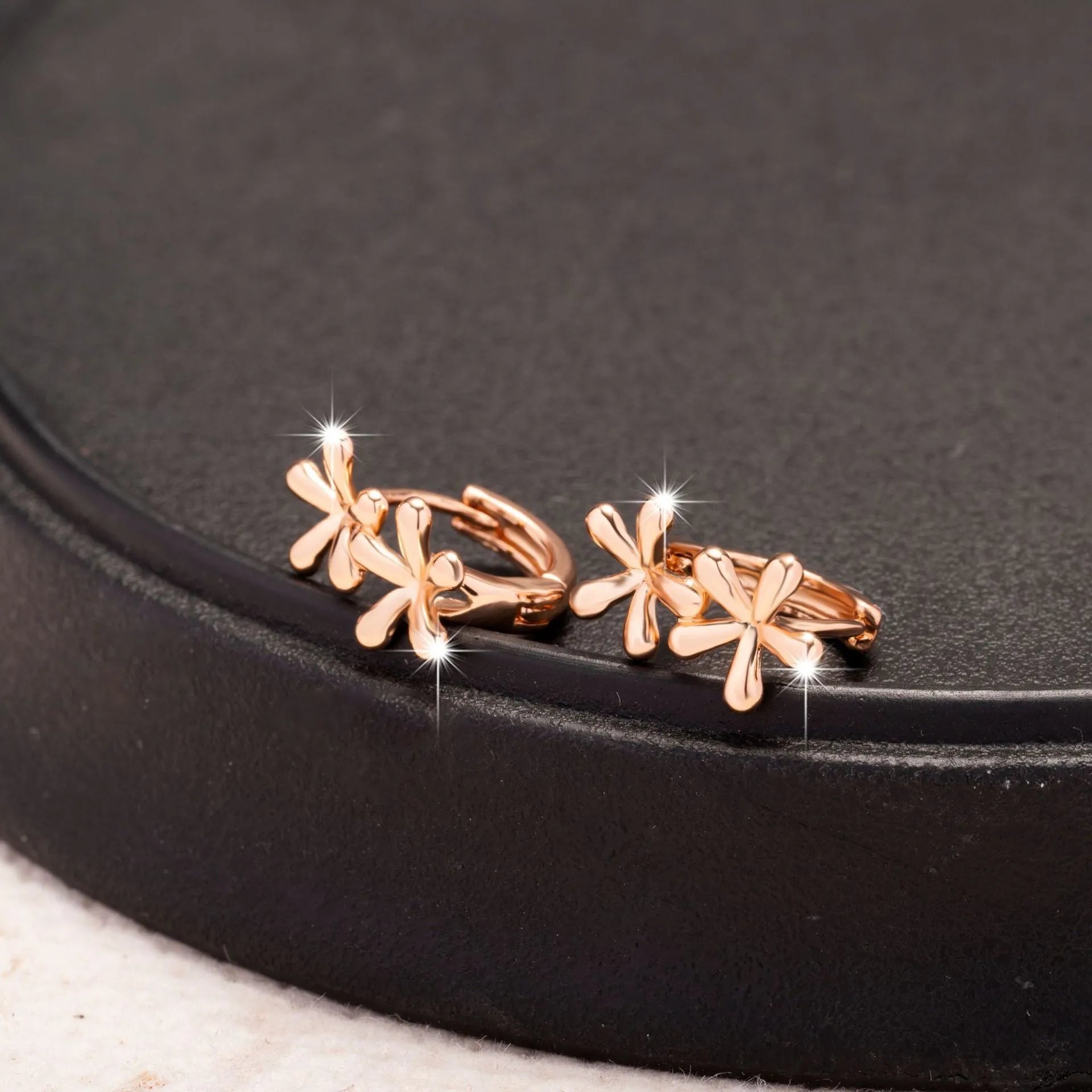 Silver rose gold electroplated circular waterdrop flower earrings with butterfly backs on a grey background.