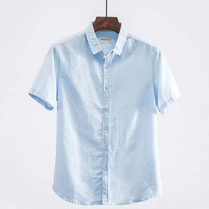 Man wearing a loose-fit light blue linen short sleeve shirt with a square collar, cardigan style.