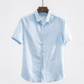 Man wearing a loose-fit light blue linen short sleeve shirt with a square collar, cardigan style.