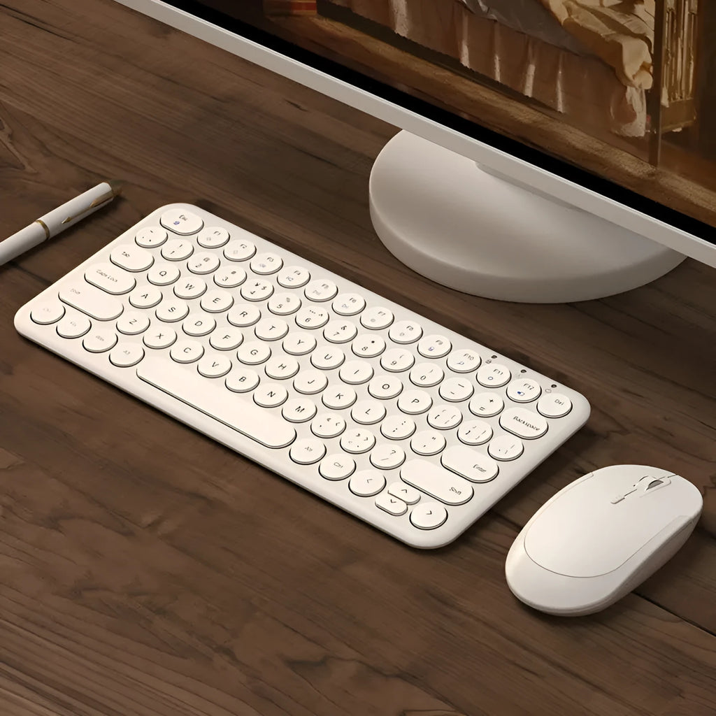 Mute white ultra-thin wireless keyboard and mouse with small USB receiver on a wooden desk.