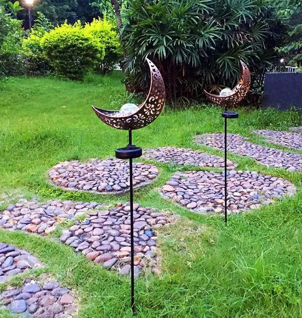 LED solar flame light with warm white glow, iron construction, and glass globe in an outdoor garden setting
