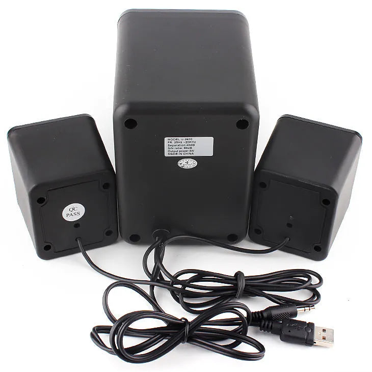Green 2.1 USB computer speaker with LED lights on a desk next to a laptop.