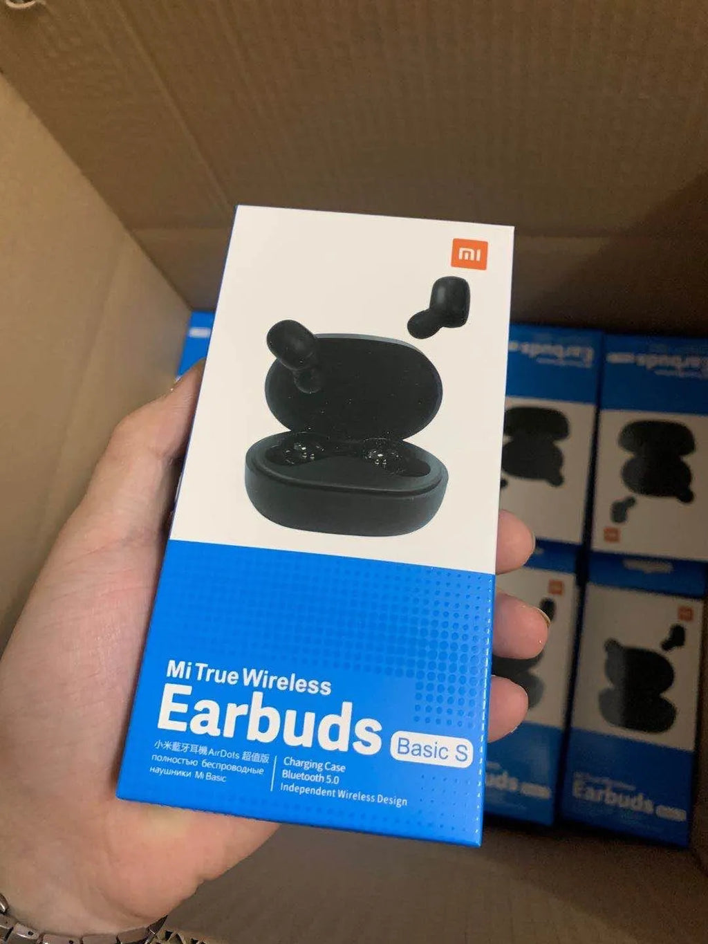 Black Redmi AirDots true wireless earbuds next to their compact charging case.