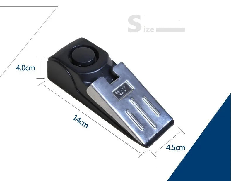 Black portable wedge door alarm with stainless steel cover placed against a hinged door.
