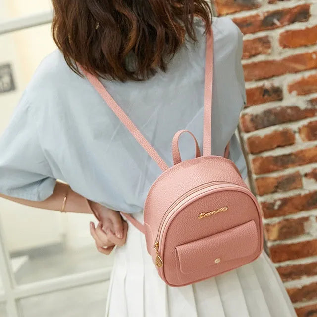 Compact black PU leather women's shoulder backpack worn crossbody, showing zipper closure and simple design.