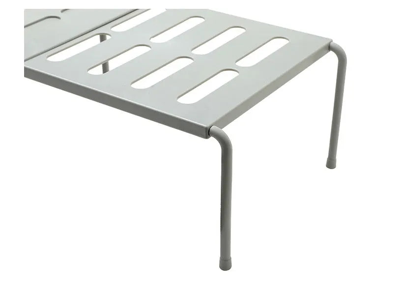 White telescopic plastic kitchen rack with single shelf, shown at adjusted height on a kitchen floor.