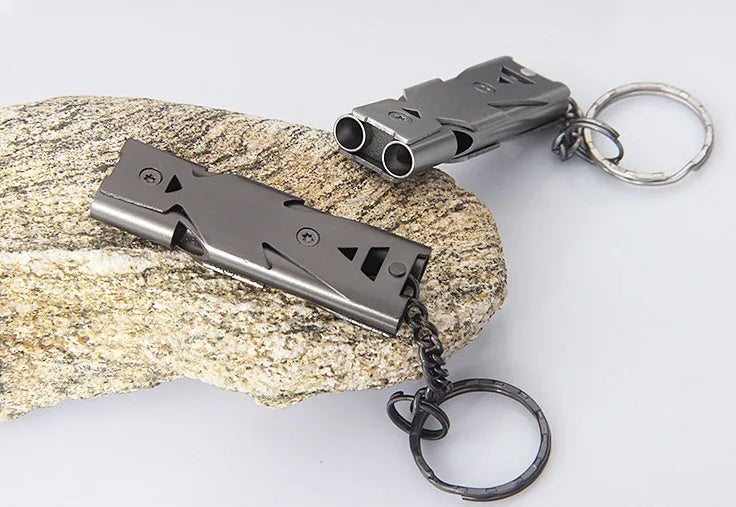 Compact metal keychain whistle with black lanyard on a keyring for outdoor emergency use