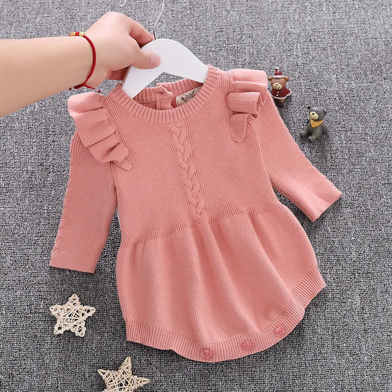 Baby girl wearing a soft pink cotton princess-style romper with a hedging placket.