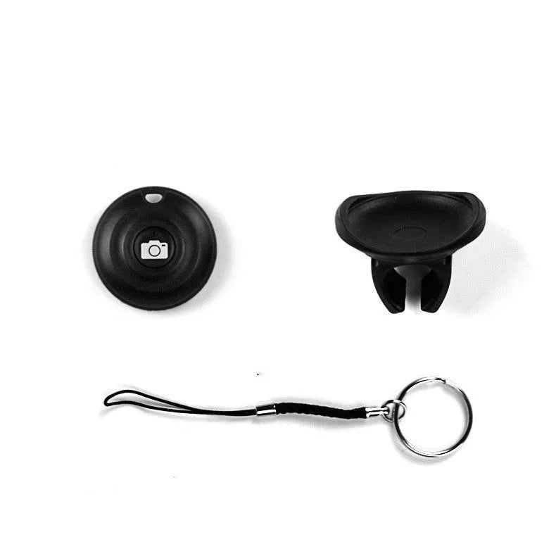 Small black Snap Bluetooth remote control for smartphone and camera shutter release, shown on a hand for scale.