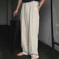 Men's apricot coloured loose-fit cotton linen suit trousers with a pencil leg on a neutral background.