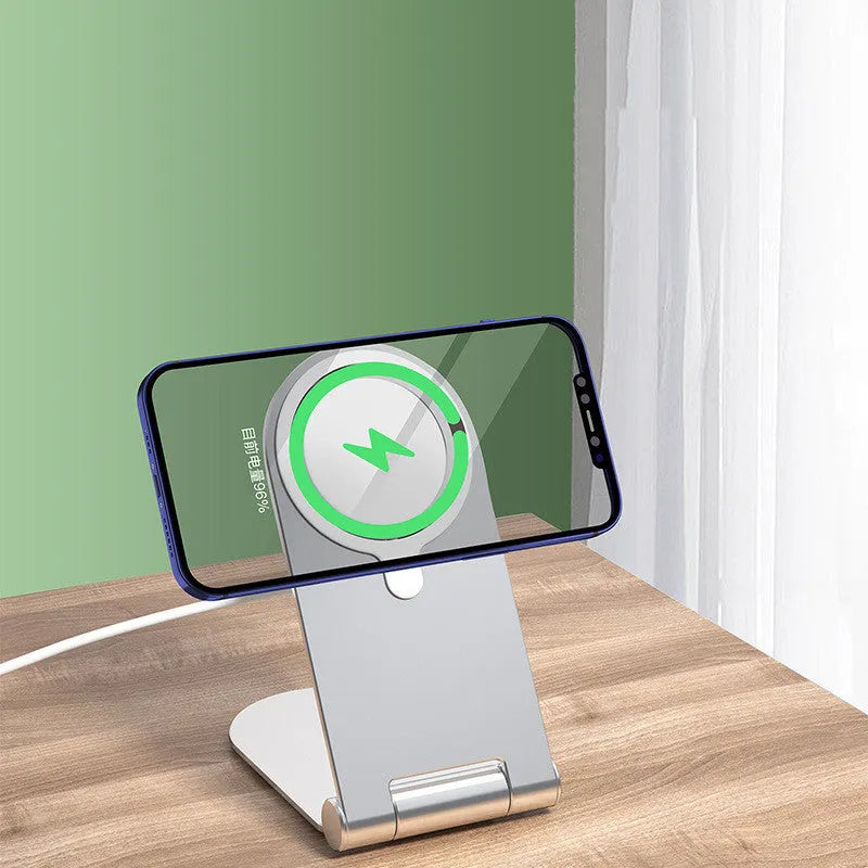 Silver aluminium alloy and plastic magnetic phone bracket for iPhone 12 on a desk.
