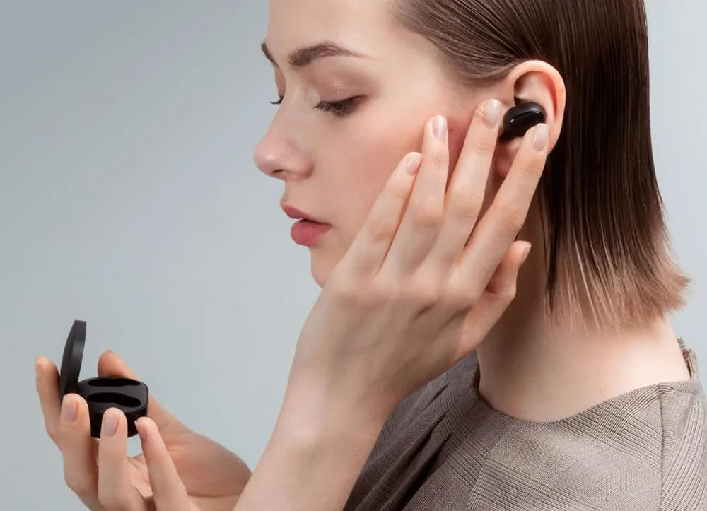 Black Redmi AirDots true wireless earbuds next to their compact charging case.