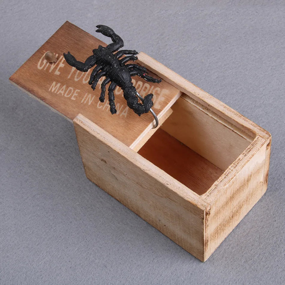 Wooden prank scare box with a lifelike spider figurine on a table.