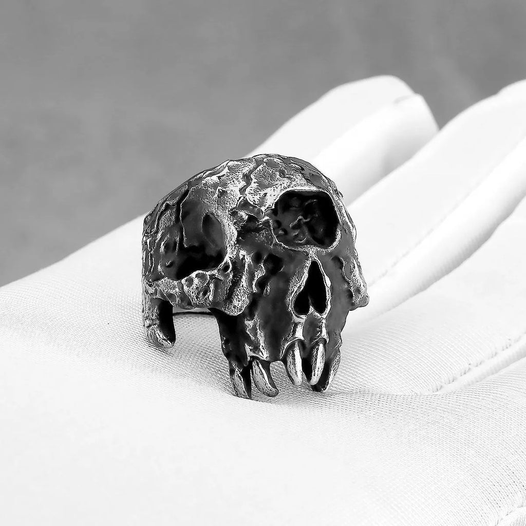 A silver-toned alloy ring featuring a detailed one-eyed skull design on a black background.