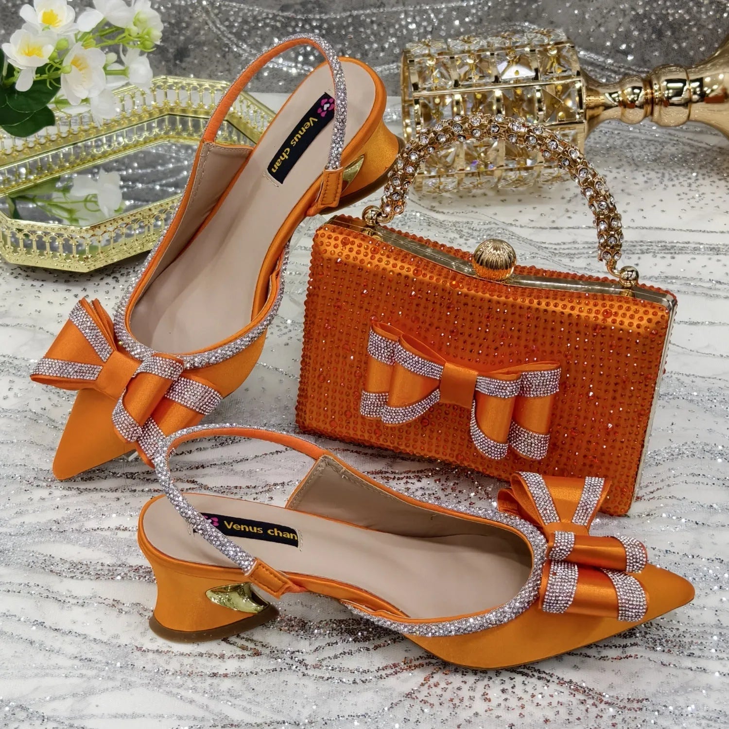 Women's black pointed sandals with mid heel, square rhinestone buckle, elastic band, and matching square bag