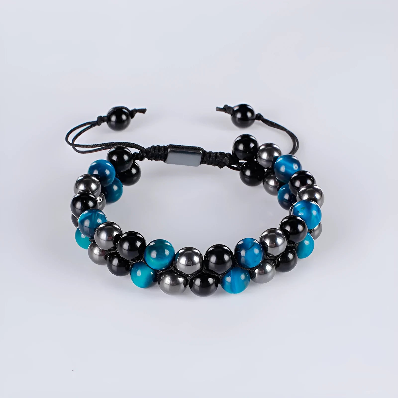 Close-up of a unisex alloy bracelet featuring green cat's eye tiger eye stones and red iron stone with an auspicious elephant charm.