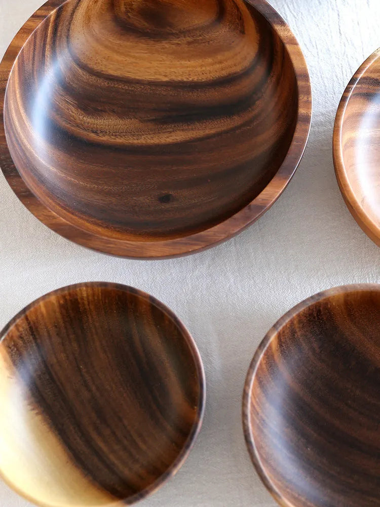 Handmade brown wooden bowl set showing multiple sizes from small to large on wooden table