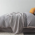 Small light grey polyester nap blanket folded, showing its texture and size.
