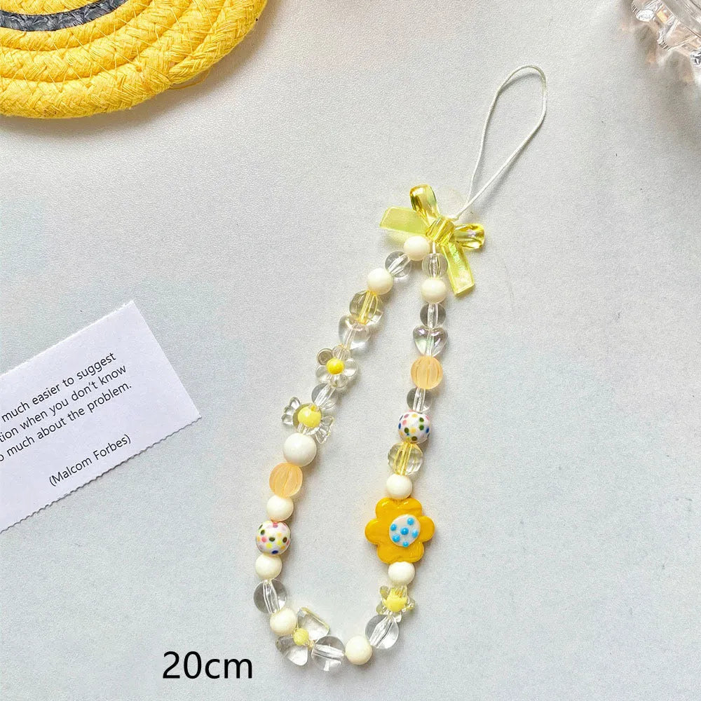 Adjustable rope wrist lanyard with blue plastic flower beads attached to a mobile phone.
