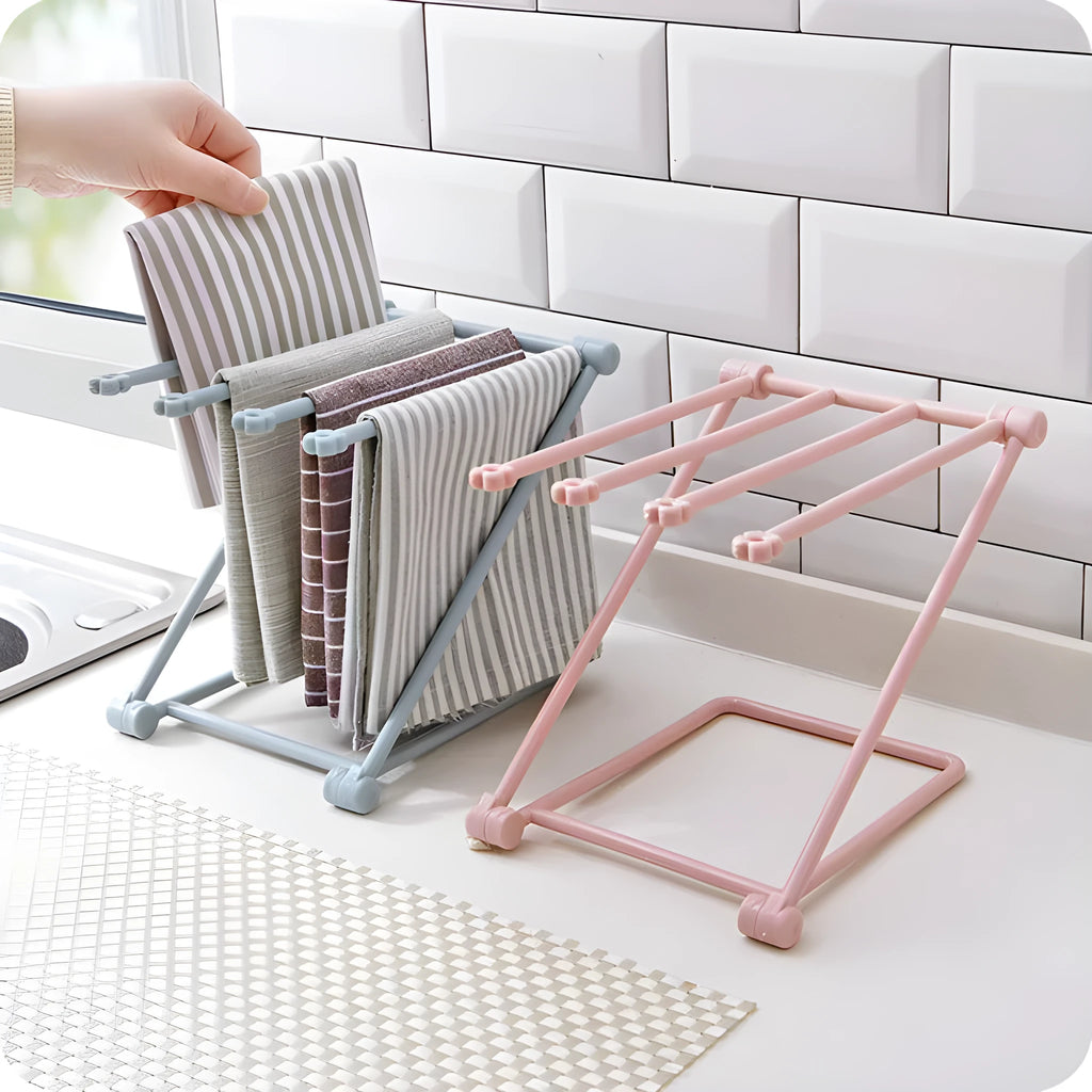 Light grey foldable plastic dishcloth shelf mounted on a wall holding towels.