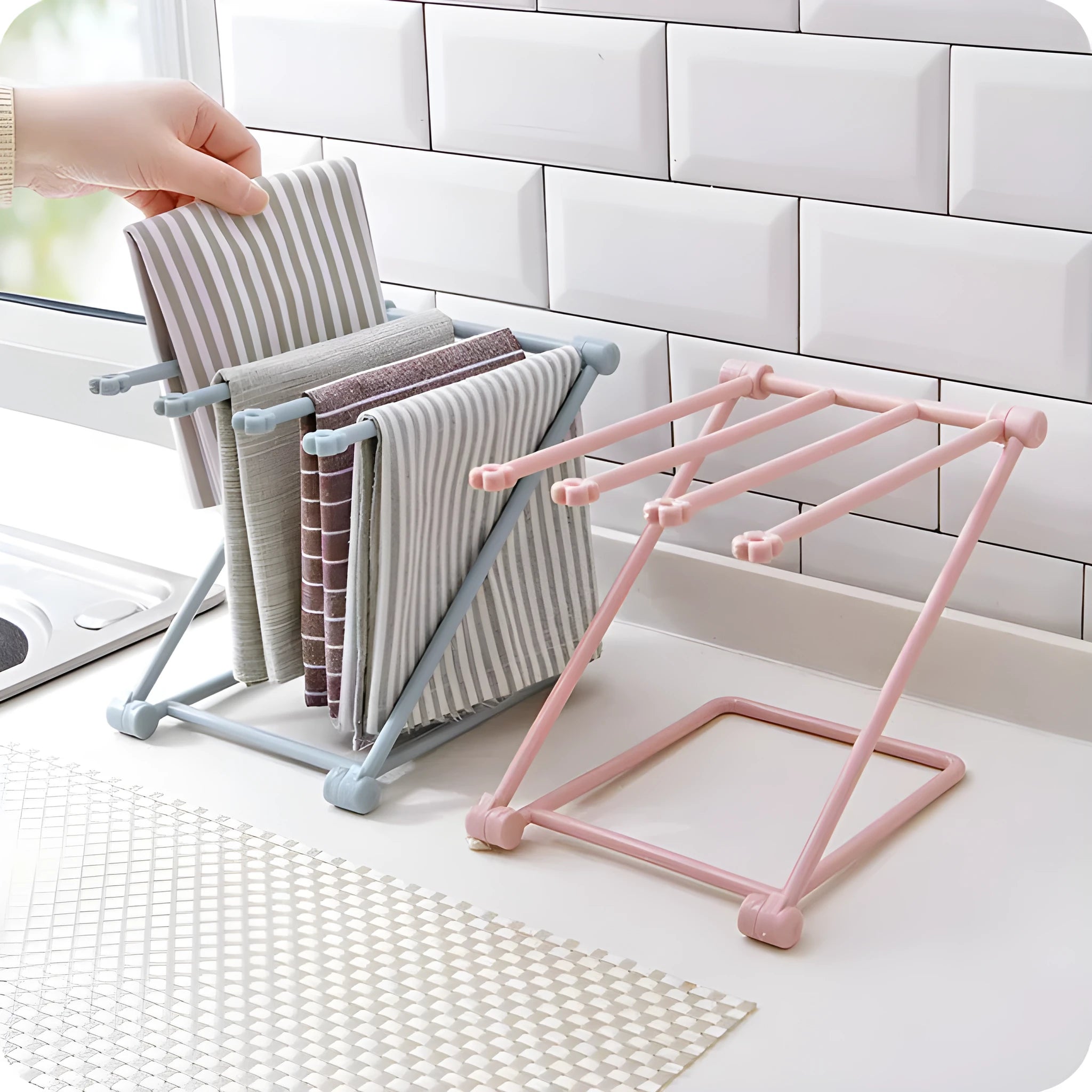 Light grey foldable plastic dishcloth shelf mounted on a wall holding towels.