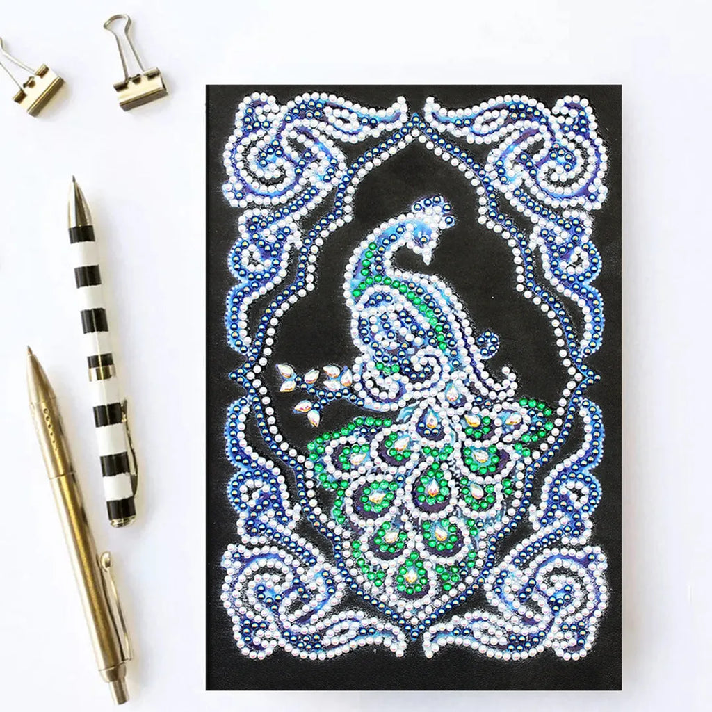 Black A5 hardcover Peacock Beauty journal open showing diamond painting canvas and organised drills in clear OPP bags.
