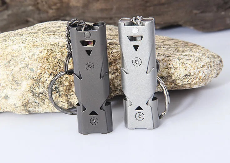 Compact metal keychain whistle with black lanyard on a keyring for outdoor emergency use