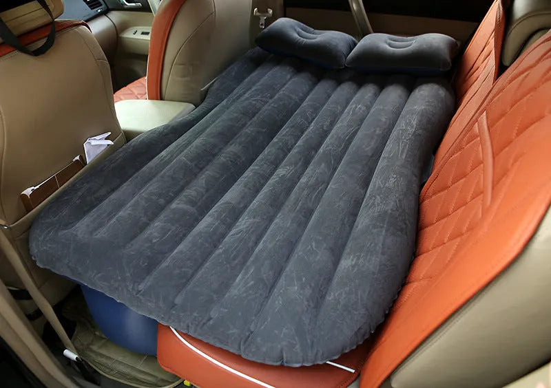 Inflatable car bed with flocked surface and pillows, set up in the back of a five-seater vehicle.