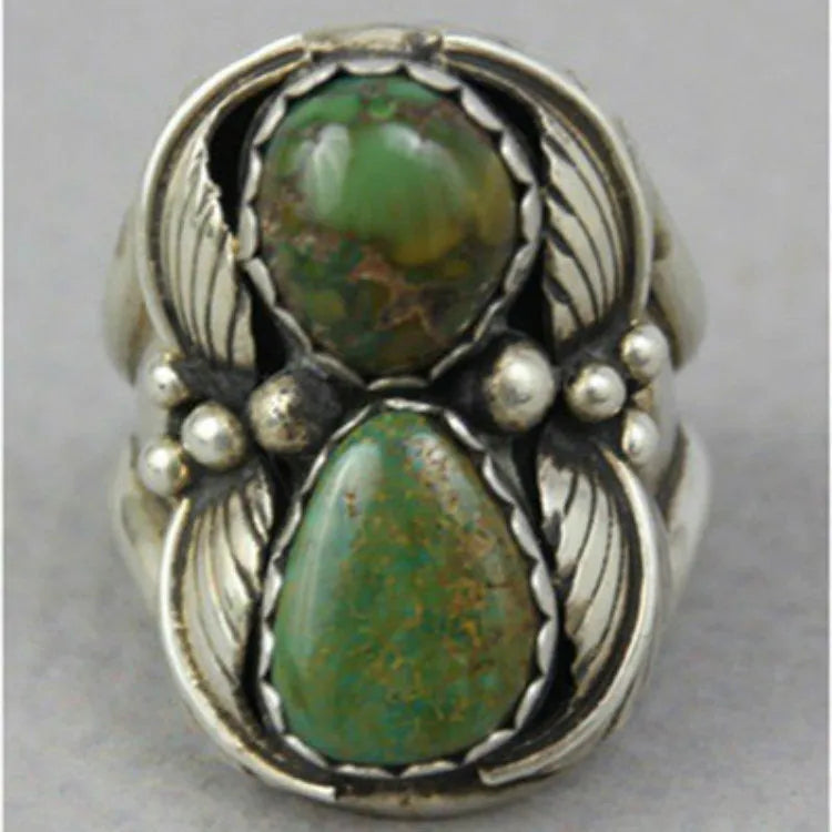 Close-up of a geometric turquoise ring with a retro inlaid design on a hand.