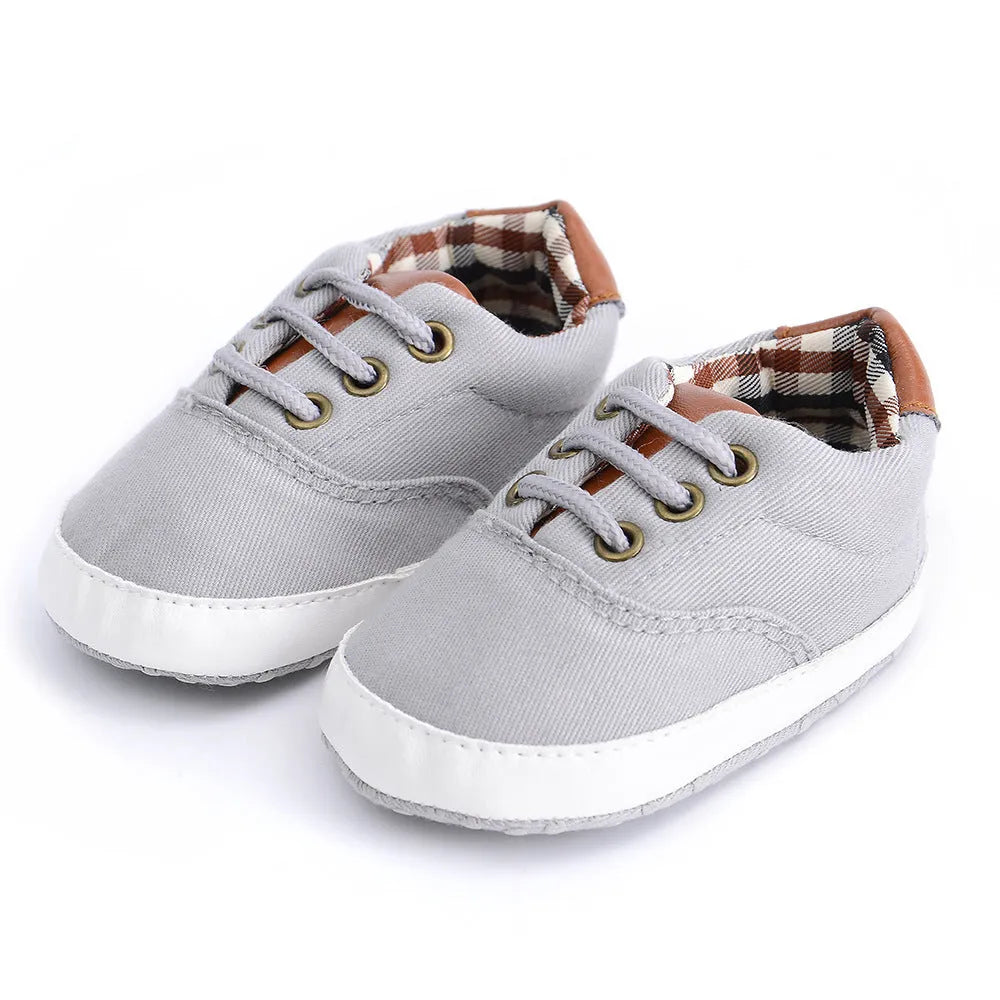 Solid colour baby canvas shoes with a front strap, shown in light grey on a white background.