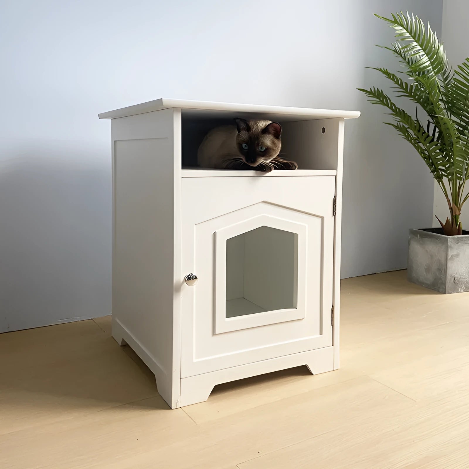 Wooden cat nest cabinet in ivory finish, with front opening for cat access, on a wooden floor