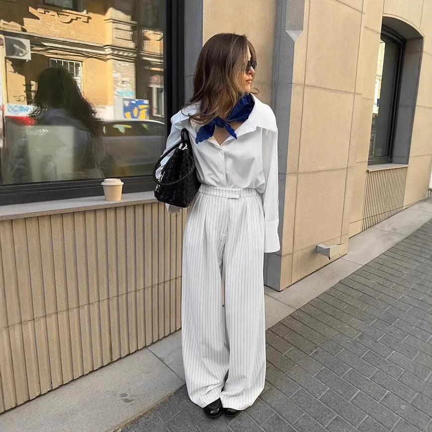 White striped wide-leg women's trousers with a front zip on a hanger.