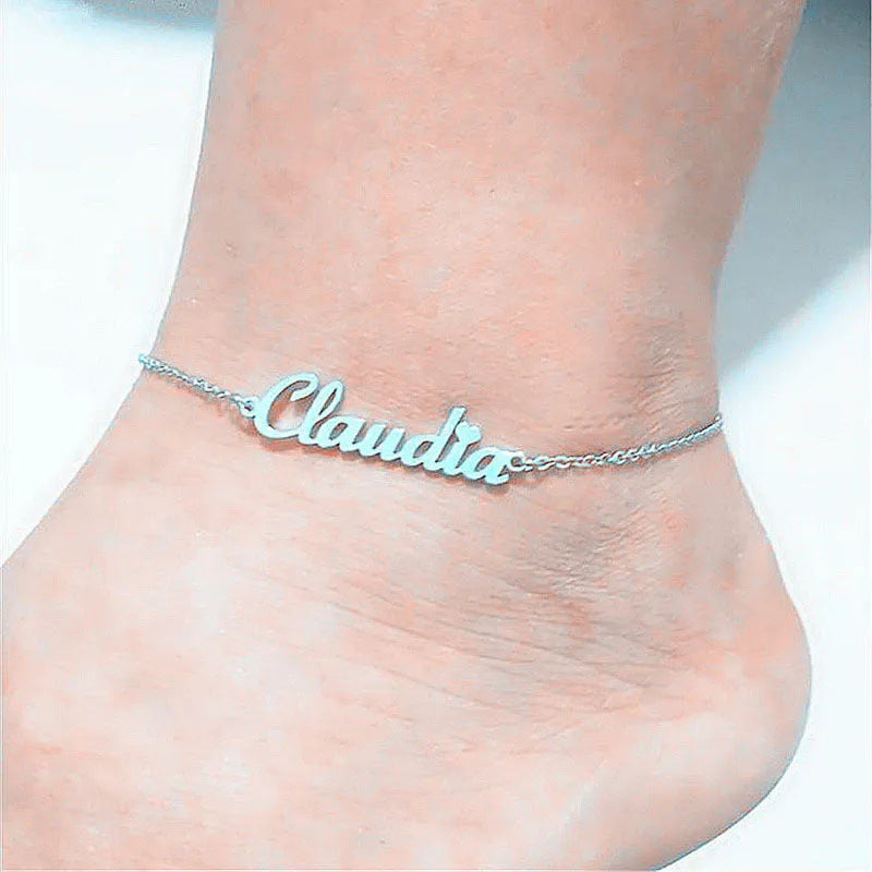Gold titanium steel cable chain anklet with personalised name engraving on a sandy beach background