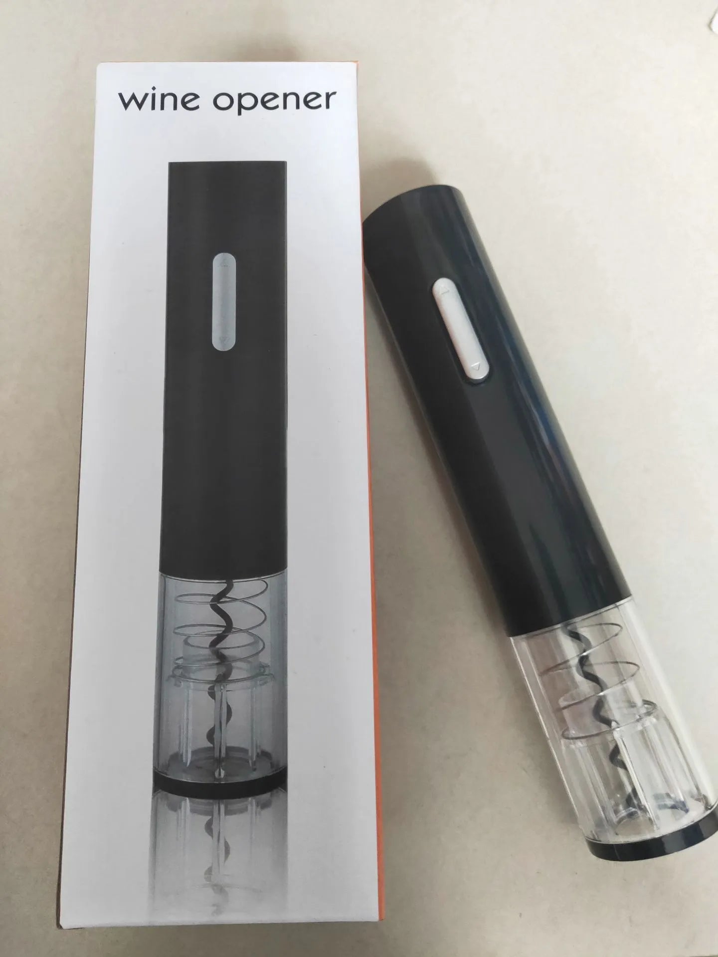 Black electric wine bottle opener with automatic corkscrew and integrated foil cutter on wooden table