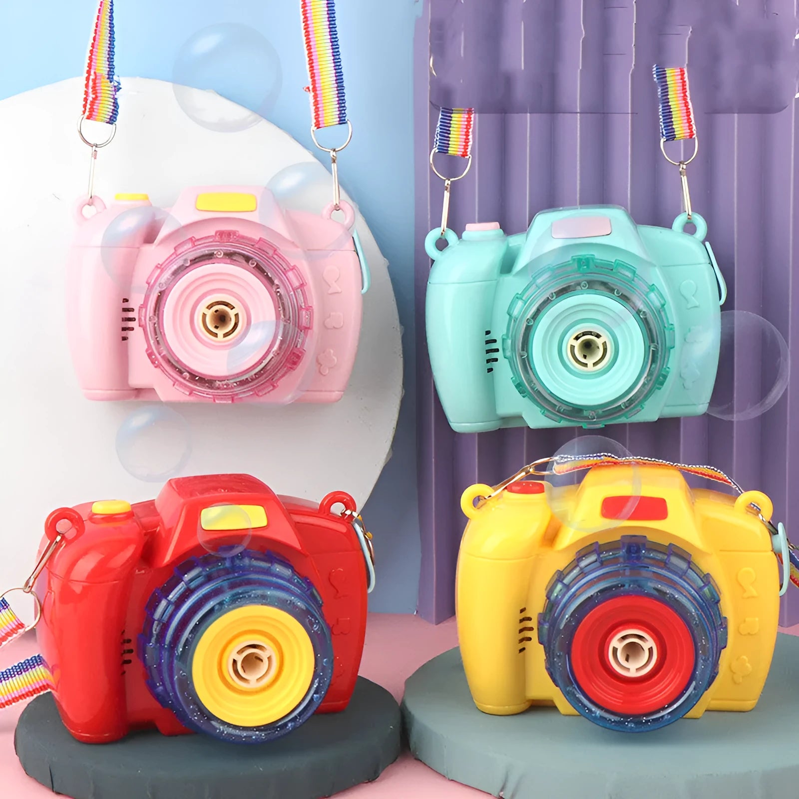 Yellow, green, red, and pink camera-shaped automatic bubble blowing machine toy for kids on a white background.