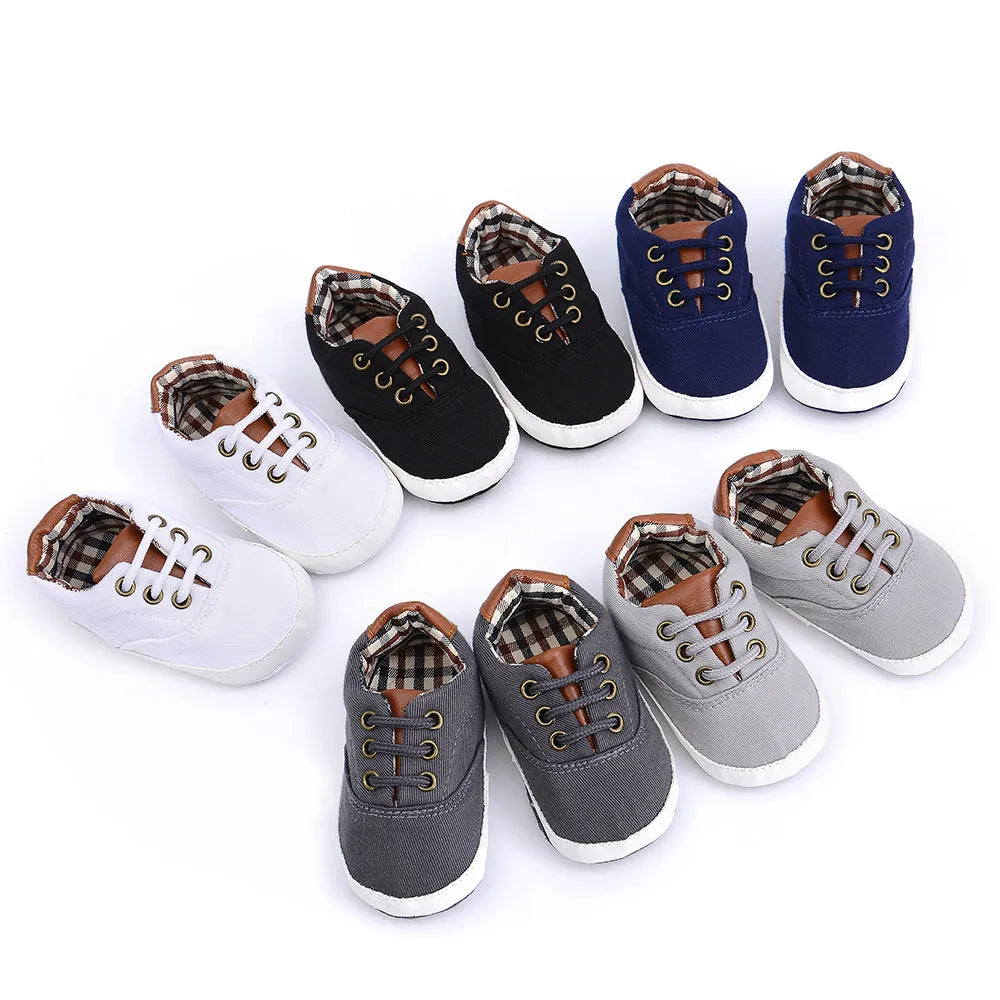 Solid colour baby canvas shoes with a front strap, shown in light grey on a white background.