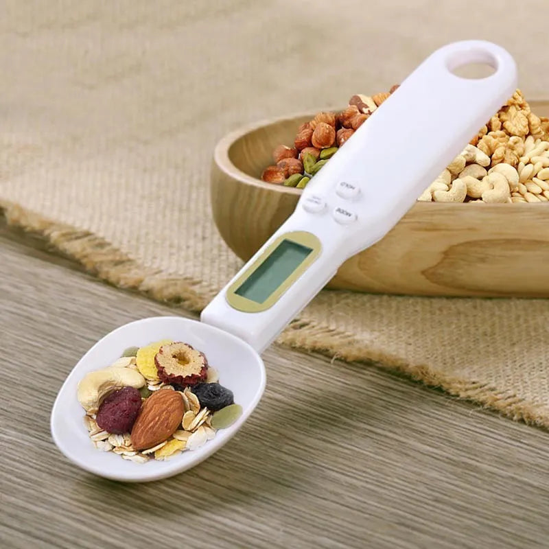 White digital spoon kitchen scale with LCD display showing weight measurement.