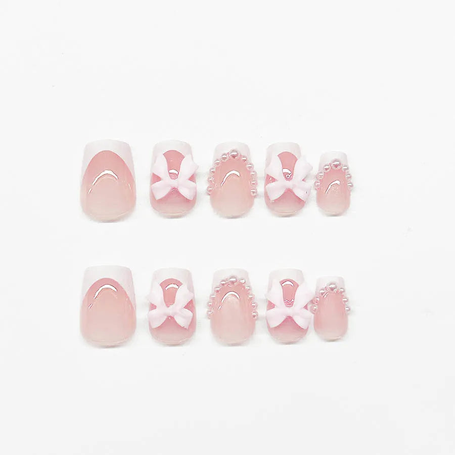 Set of 24 white French manicure false nails with bow and tulip designs, next to bottles of S274 glue and jelly glue.