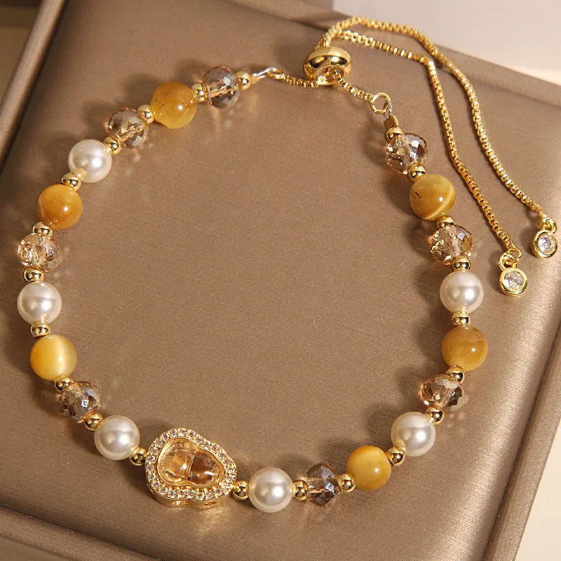Yellow tiger's eye glass gourd pendant bracelet with alloy inlay and stone accents on a wrist.