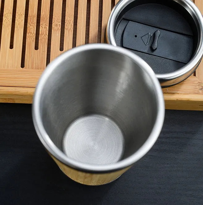 Bamboo travel coffee cup with stainless steel interior, leak-proof lid, and a grey foam pad.