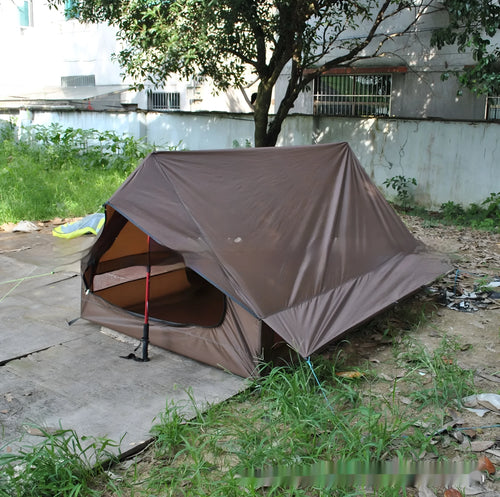 Brown A-Line pole-free cabin tent set up in a forest, showing its spacious interior for 2-3 people.