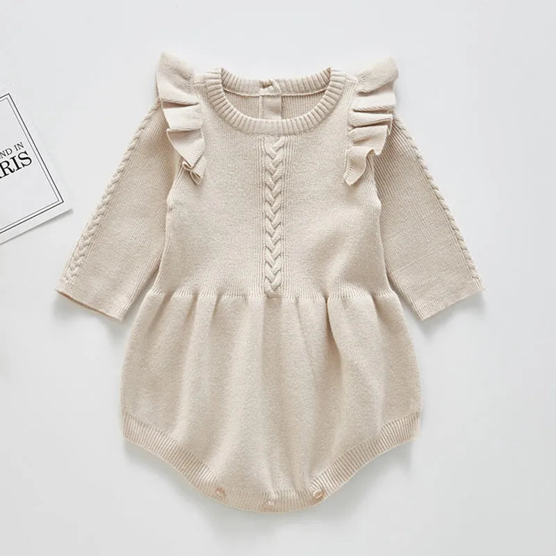 Baby girl wearing a soft pink cotton princess-style romper with a hedging placket.